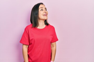 Middle age hispanic woman wearing casual clothes looking away to side with smile on face, natural expression. laughing confident.