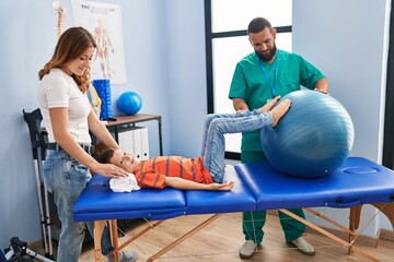 Family having rehab session using fit ball at rehab clinic