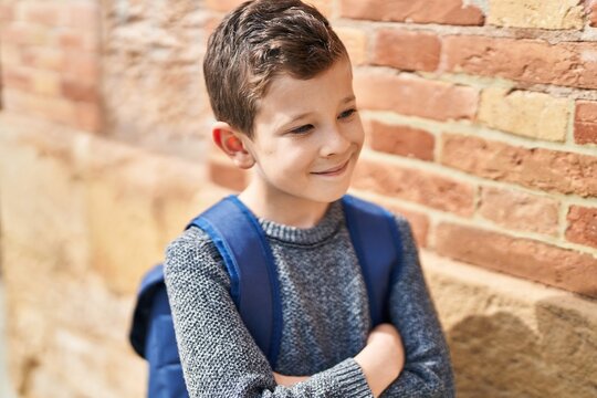 Blond child student smiling confident standing with arms crossed gesture at street