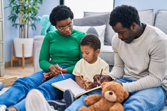 African american family drawing on notebook sitting on floor at home