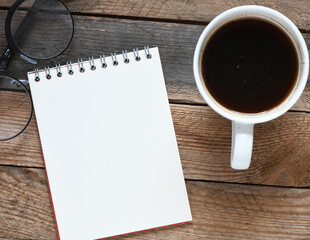Blank notepad and coffee cup on office wooden table