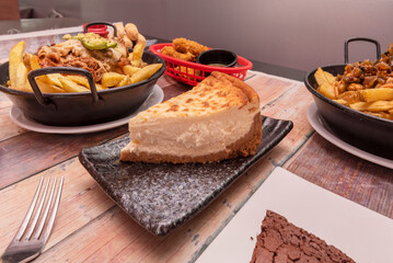 fast food dishes and snacks on a table with cheesecake dessert in the foreground