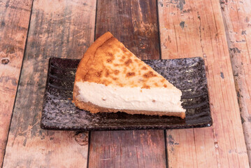 Freshly baked cheesecake dessert slice on black porcelain plate