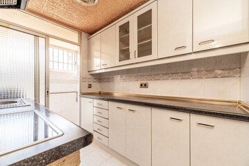 kitchen with furniture on both sides, with black countertop and exit to drying terrace with glass and aluminum sliding doors