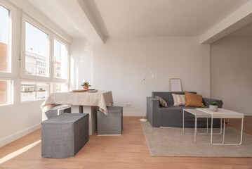 Living room with dining table next to the window with lots of light, two-seater sofa and coffee tables
