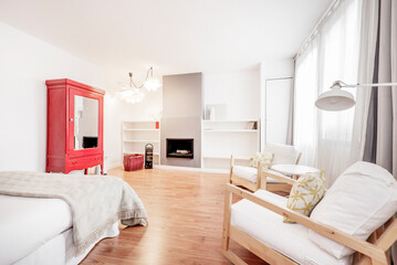 bedroom with double bed, red wooden wardrobe with mirror doors and armchairs with matching wooden table and fireplace with built-in shelves