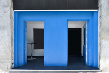 Fototapeta premium Facade of a local with walls painted in blue and black poster, table with chrome foot and black vinyl floor