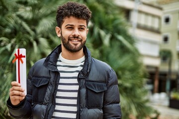 Young arab man holding anniversary present outdoor at the town