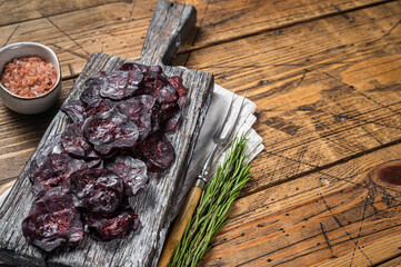 Horse game meat cured sausage with rosemary on a cutting board. Wooden background. Top view. Copy...