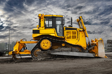 Bulldozer machine is leveling construction site. Earthmover with tractor is moving earth. Close-up. Construction heavy machinery.