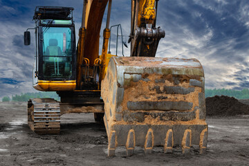 Powerful excavator at a construction site against a blue cloudy sky. Earthmoving construction equipment. Modern building machines.