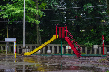 雨に濡れた神社の境内にある遊具