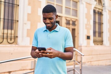 Young african american man smiling confident using smartphone at street