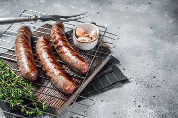 Grilled beef and lamb meat sausages with rosemary herbs on grill. Gray background. Top view. Copy...