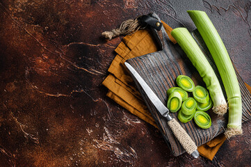 Sliced Green Leeks on wooden cutting board. Dark background. Top view. Copy space