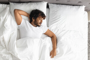 Top view of indian guy sleeping alone in bed