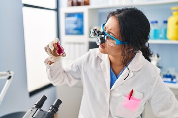 Young chinese woman wearing scientist uniform examining geode at laboratory