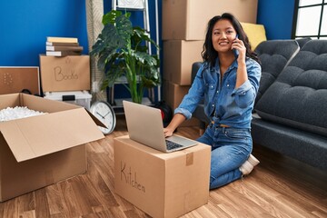 Young chinese woman smiling confident using laptop and talking on the smartphone at home