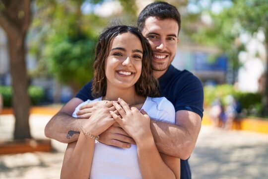 Young hispanic couple smiling confident hugging each other at park