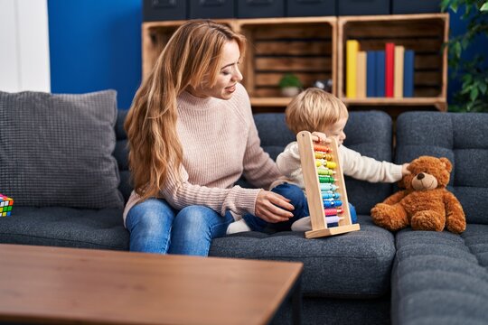 Mother and son playing with abacus sitting on sofa at home