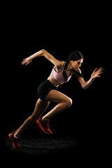 Studio shot of young muscular woman running isolated on black background. Sport, track-and-field...