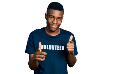 Young african american man wearing volunteer t shirt pointing fingers to camera with happy and...