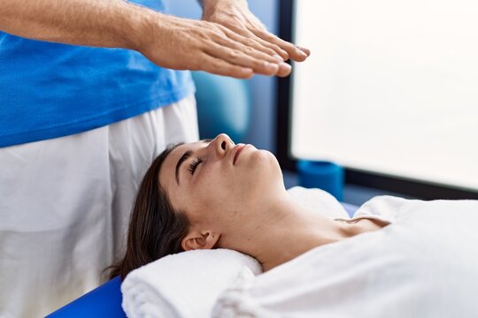 Man and woman wearing physiotherpy uniform having reiki therapy session at clinic