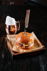 Juicy beef burger with knife on wooden table.