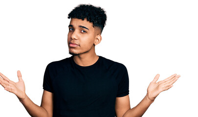 Young african american man wearing casual black t shirt clueless and confused with open arms, no...