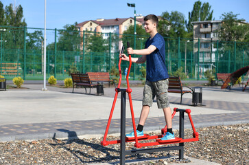 a teenage boy trains on a sports ground outdoors, he does physical exercises, a healthy lifestyle, a bright sunny day in summer