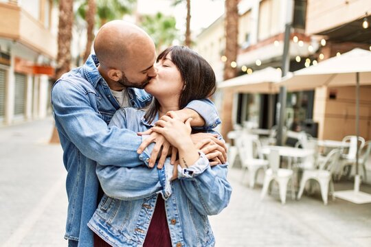 Young hispanic couple kissing and hugging at the city.