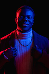 Neon light portrait. Happy man. 80s fashion. Cheerful stylish attractive hipster guy in retro bright red glow isolated on dark studio background.