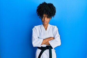 African american woman with afro hair wearing karate kimono and black belt skeptic and nervous,...