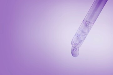 Glass lab dropper with a drop hanging from it on violet background, Abstract cosmetic ingredients...
