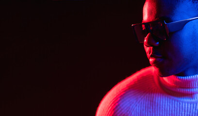 Neon man banner. Eyewear fashion. Cyberpunk style. Portrait of handsome cheerful guy in sunglasses red bright light isolated on black empty space background.