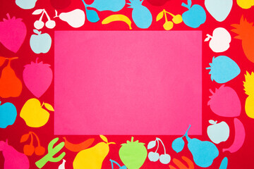pink blank paper around which is red paper full of colorful paper fruits, creative summer design, abstract background

