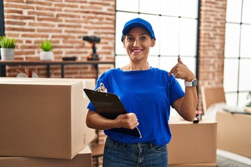 Middle age brunette woman wearing delivery uniform at house moving pointing finger to one self smiling happy and proud