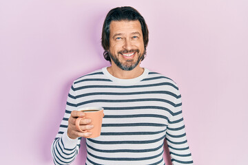 Middle age caucasian man drinking a cup of coffee looking positive and happy standing and smiling with a confident smile showing teeth