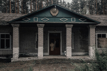 Fototapeta na wymiar An old building in an abandoned pioneer camp. Emblem of the USSR. Beautiful nature. Ancient architecture. Mystical abandoned building.