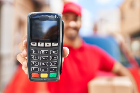 Young hispanic man courier holding package and data phone at street - Powered by Adobe