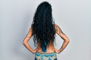 Young woman wearing bindi and traditional belly dance clothes standing backwards looking away with...