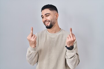 Young handsome man standing over isolated background showing middle finger doing fuck you bad...