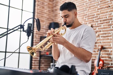 Young arab man musician playing trumpet at music studio