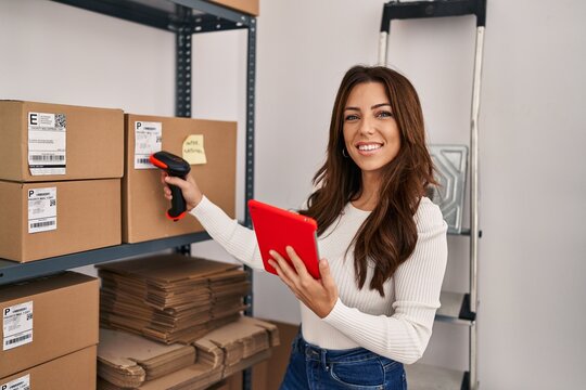 Young hispanic woman ecommerce business worker scanning package using barcode reader at office