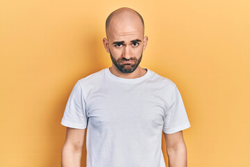 Young bald man wearing casual white t shirt depressed and worry for distress, crying angry and afraid. sad expression.