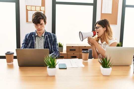 Businesswoman angry shouting her partner using megaphone at the office.