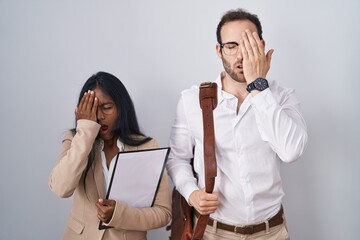 Interracial business couple wearing glasses yawning tired covering half face, eye and mouth with hand. face hurts in pain.