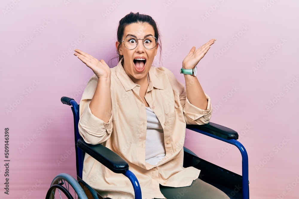 Canvas Prints Young hispanic woman sitting on wheelchair celebrating crazy and amazed for success with arms raised and open eyes screaming excited. winner concept