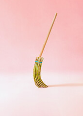 Creative surreal composition with broom made of fresh asparagus against pastel pink background. Trendy detox and healthy lifestile concept.