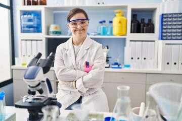 Hispanic girl with down syndrome working at scientist laboratory happy face smiling with crossed arms looking at the camera. positive person.